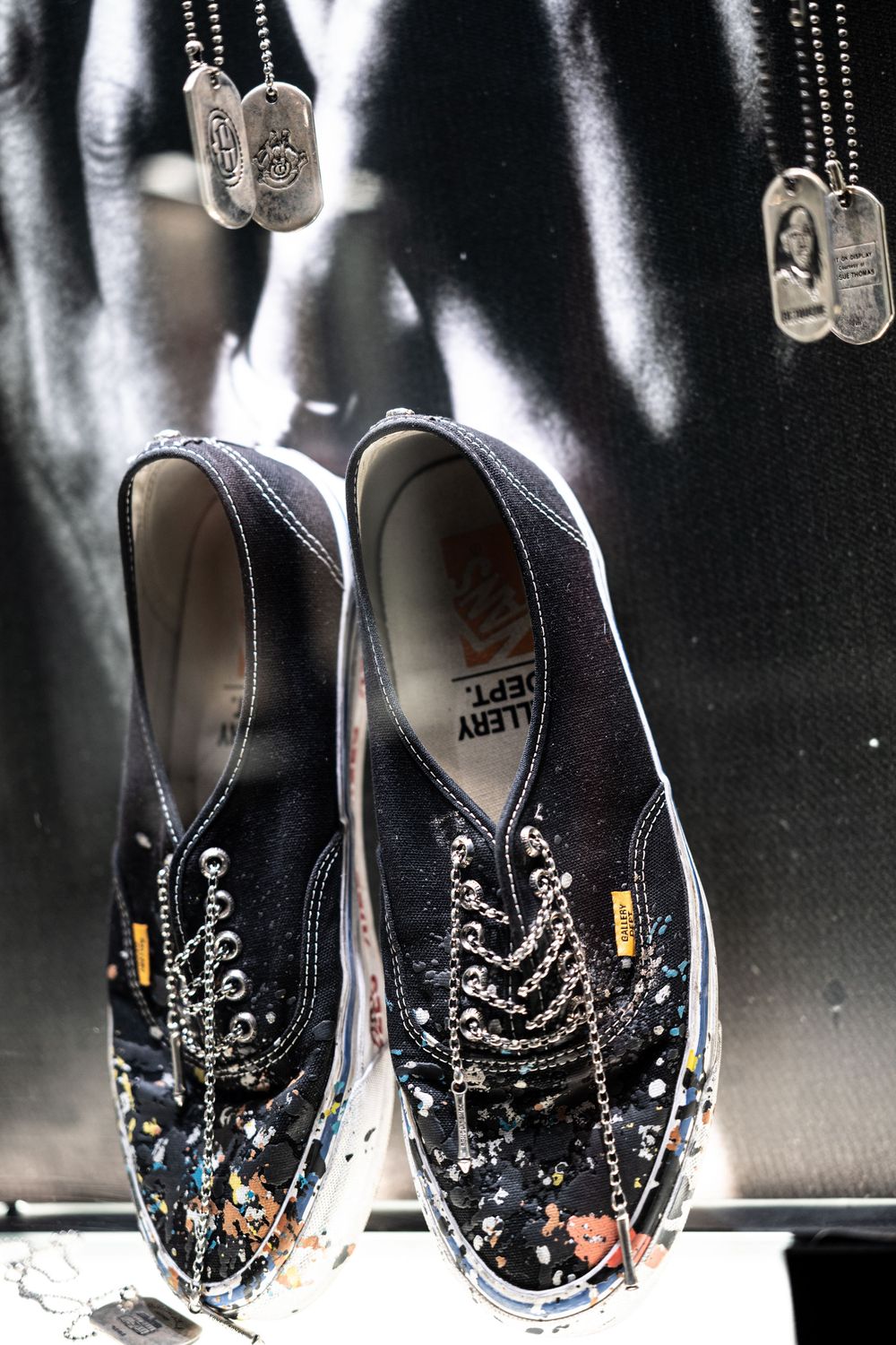 Gallery Dept. x Vans black sneakers with paint splatter details displayed with military dog tags.