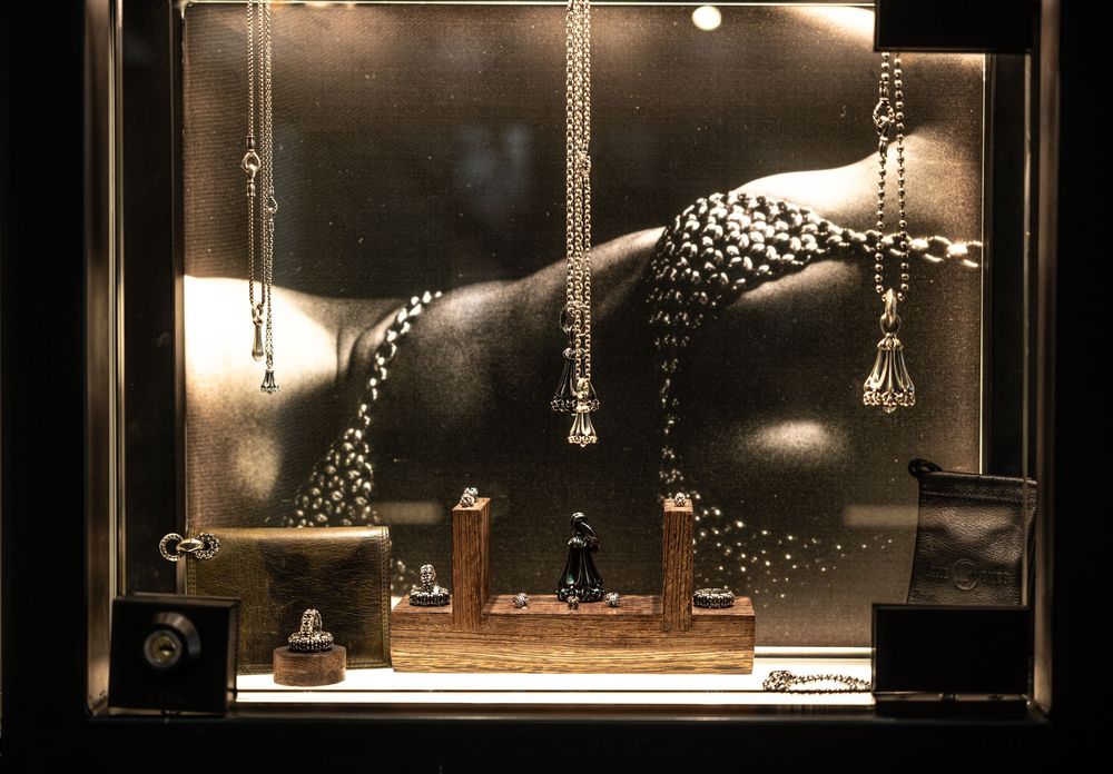 Luxury jewelry store window display featuring pearl necklaces and accessories against a dramatic dark backdrop.