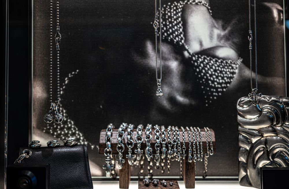Luxury silver jewelry display with pearl necklaces and bracelets against a dramatic black and white backdrop.