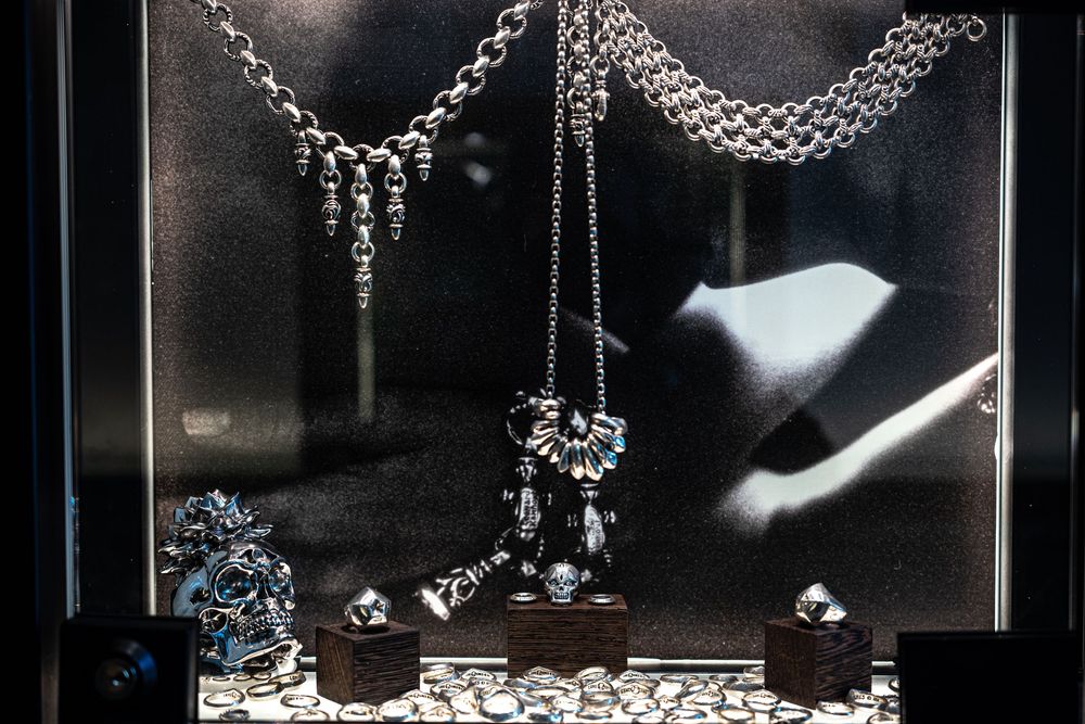 Elegant silver jewelry display featuring necklaces, chains, and ornate pieces arranged in a dark luxury showcase.