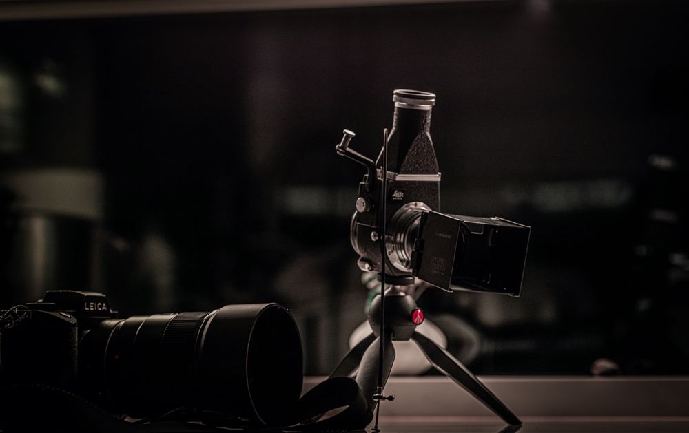 Professional camera on a tripod with a microphone attachment in a dark studio setting.