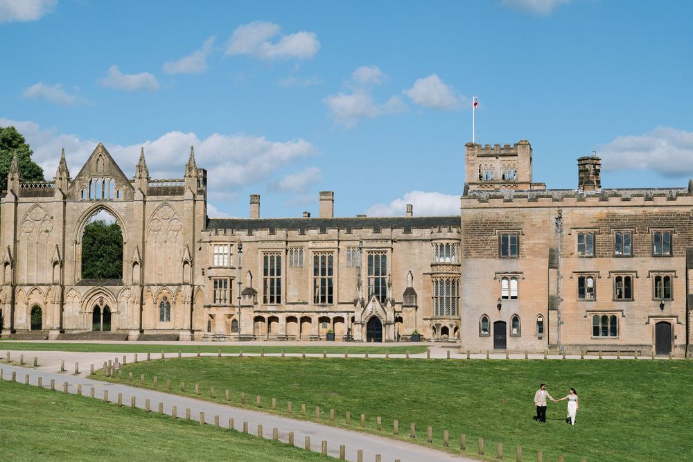 Historic Newstead Abbey estate with Gothic architecture, green lawns, and blue sky in Nottinghamshire, England.