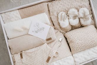Neutral-toned baby gift box with blanket, slippers, onesie, pacifier clip, and personalized name card.