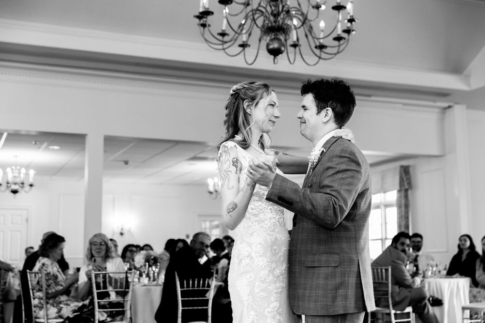 Bride and groom share their first dance at an elegant wedding reception in black and white photo.