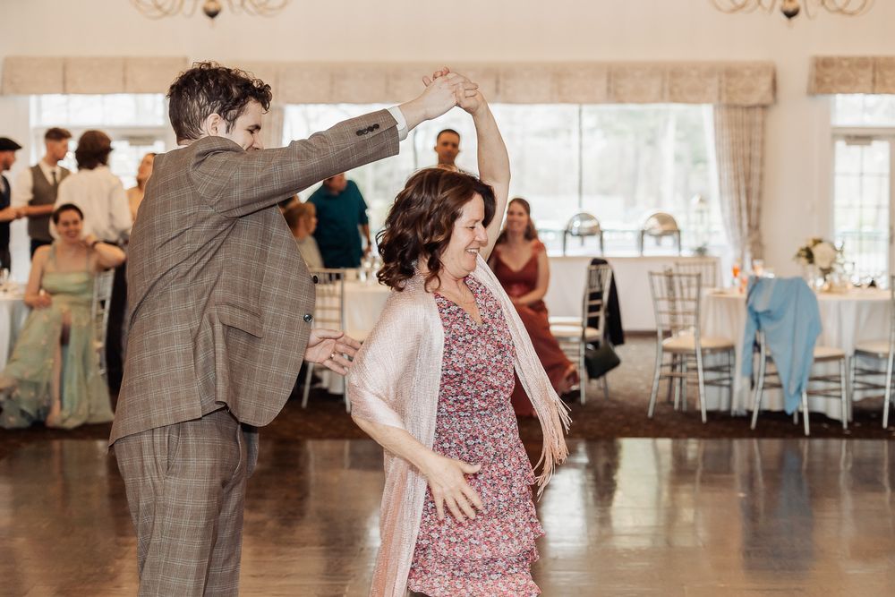 Guests enjoy lively dancing at a wedding reception in a beautifully decorated ballroom venue.