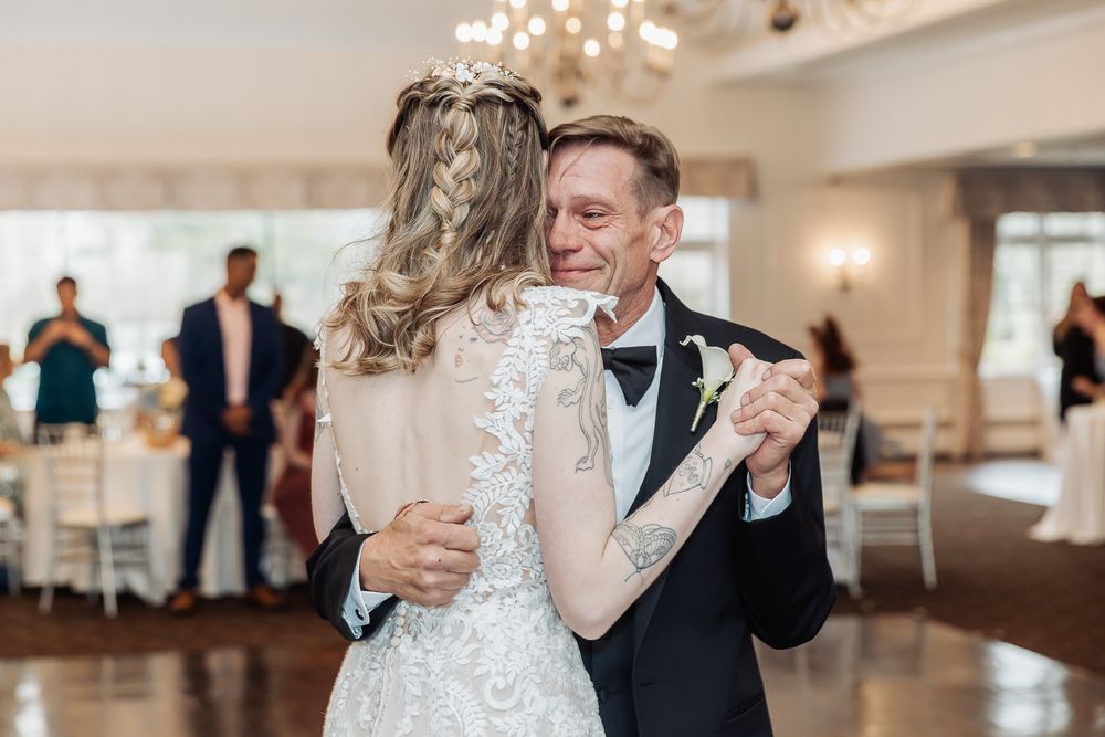 Bride and groom share an emotional first dance at elegant wedding reception with chandelier backdrop.