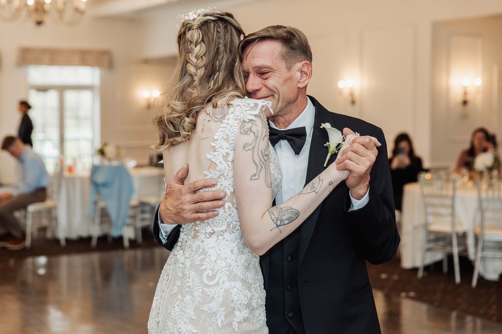 Bride and groom share an emotional first dance, embracing and smiling in an elegant wedding reception venue.
