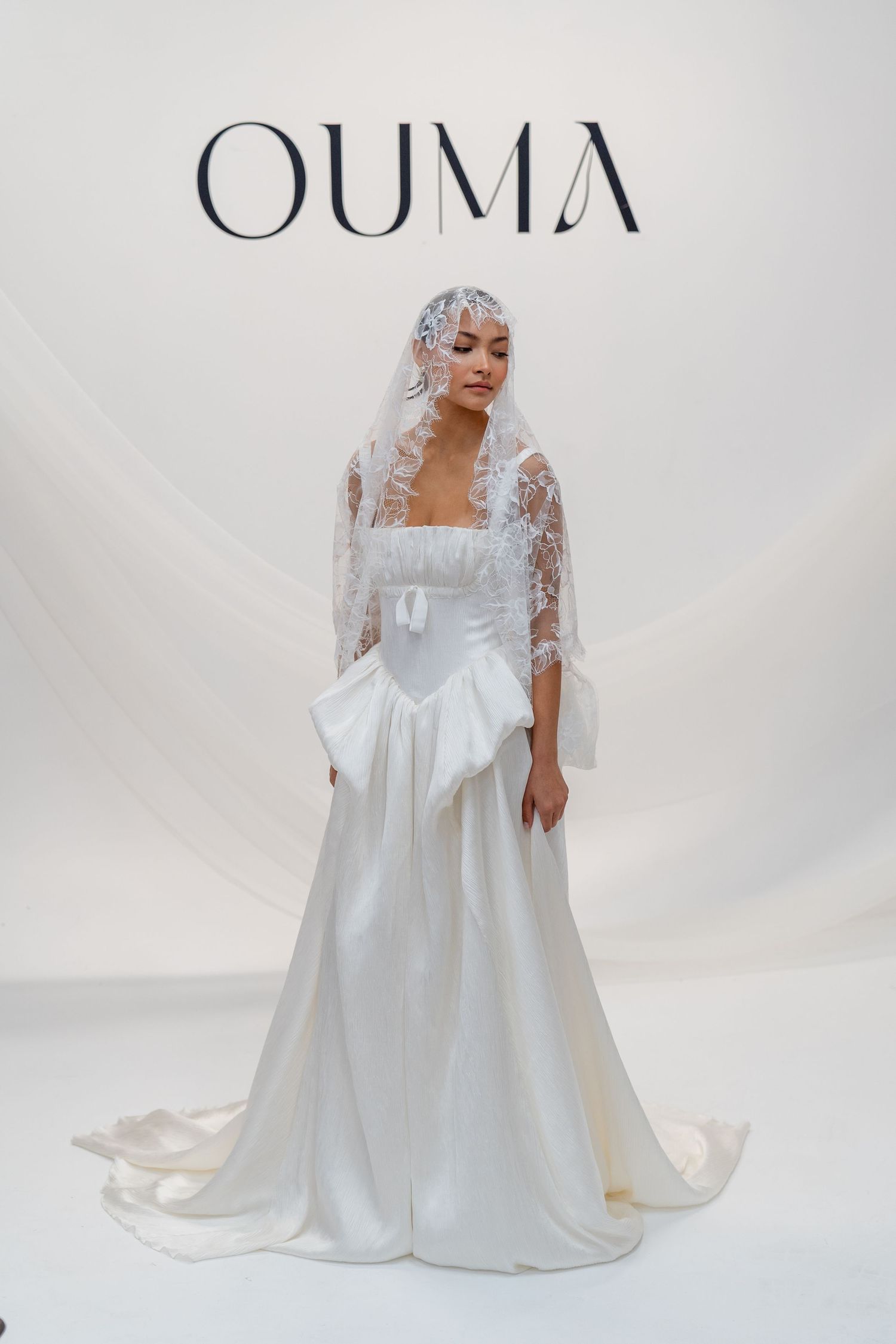 Elegant OUMA bridal gown with lace veil, square neckline, and flowing white skirt with bow detail.
