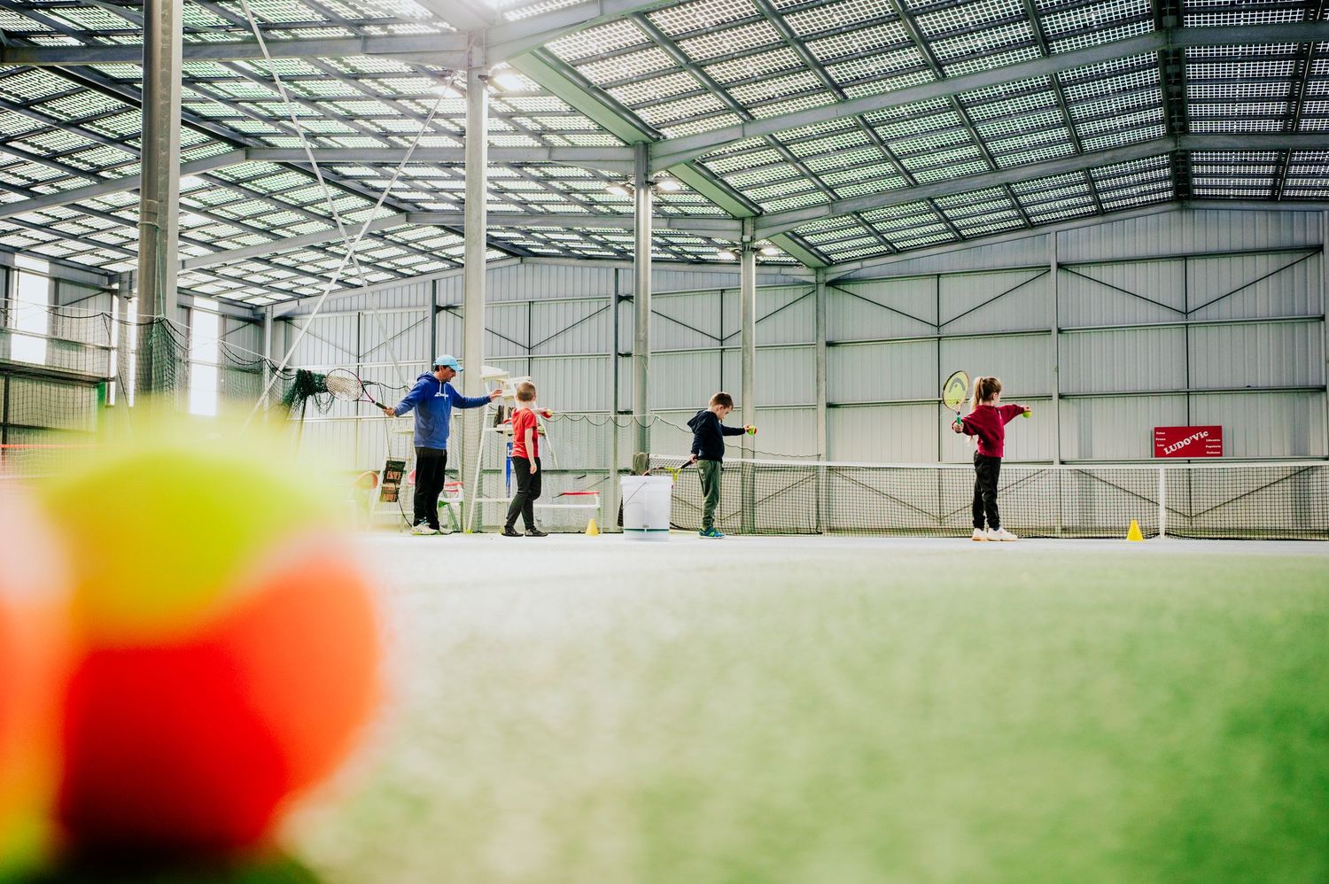 Enfants jouant au tennis de dos sous une ombrière solaire, dans le respect du droit à l’image.