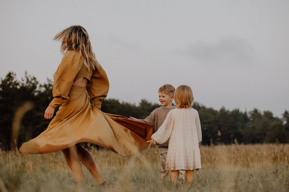 A family walks together through a golden field at sunset while a dress flows dramatically in the evening breeze.