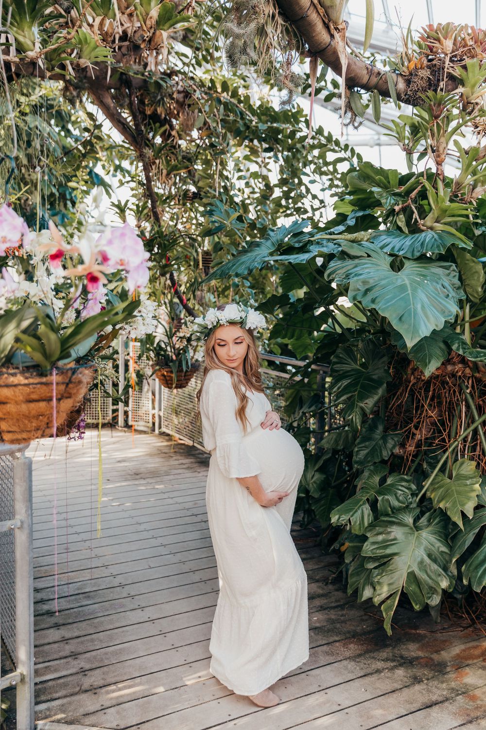 Beautiful maternity session on wooden deck with tropical plants and flowers.