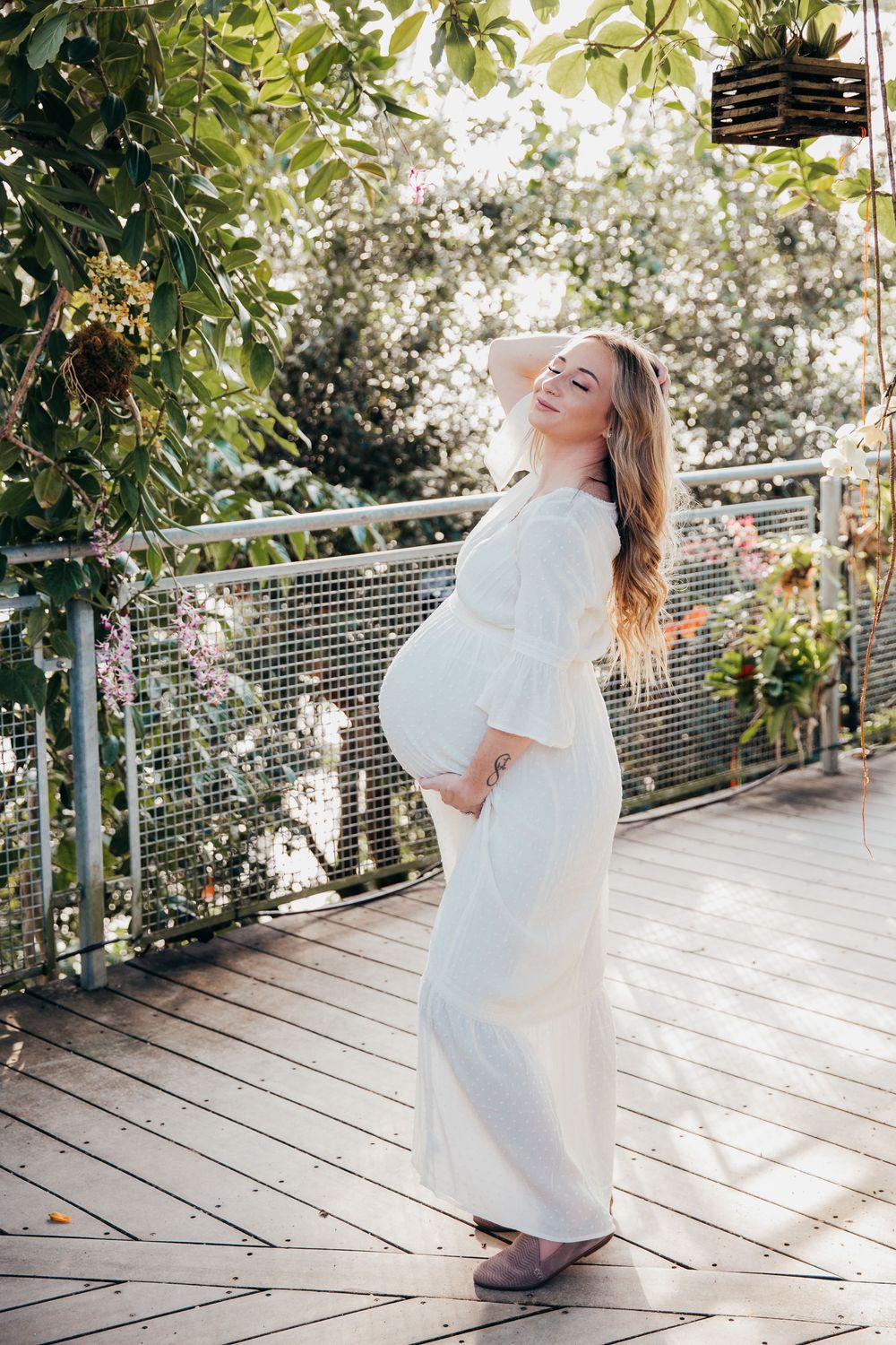 Light-filled greenhouse maternity photos with rustic wooden deck and natural elements.