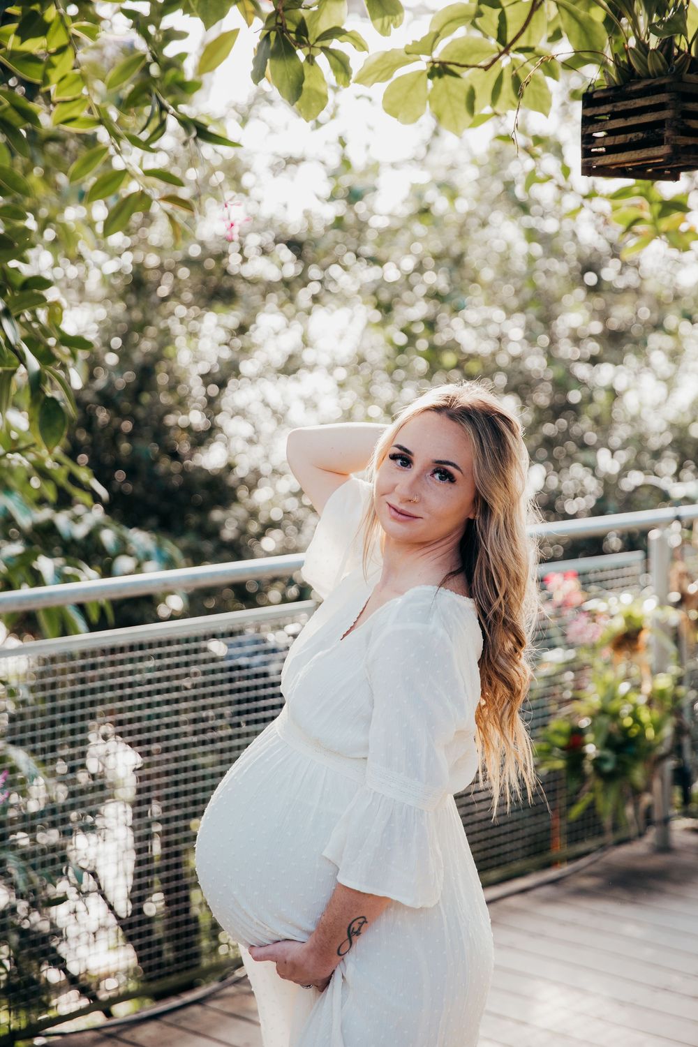 Sun-drenched maternity portraits in an indoor garden setting.
