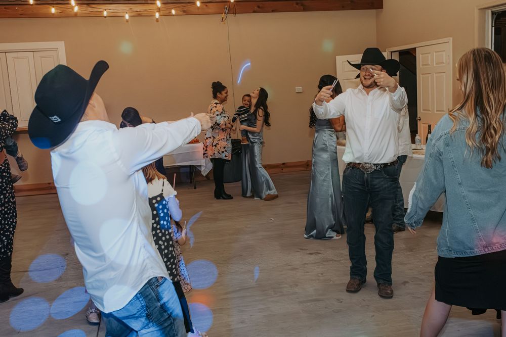 People dancing and having fun at an indoor party with string lights hanging from wooden beams on the ceiling.