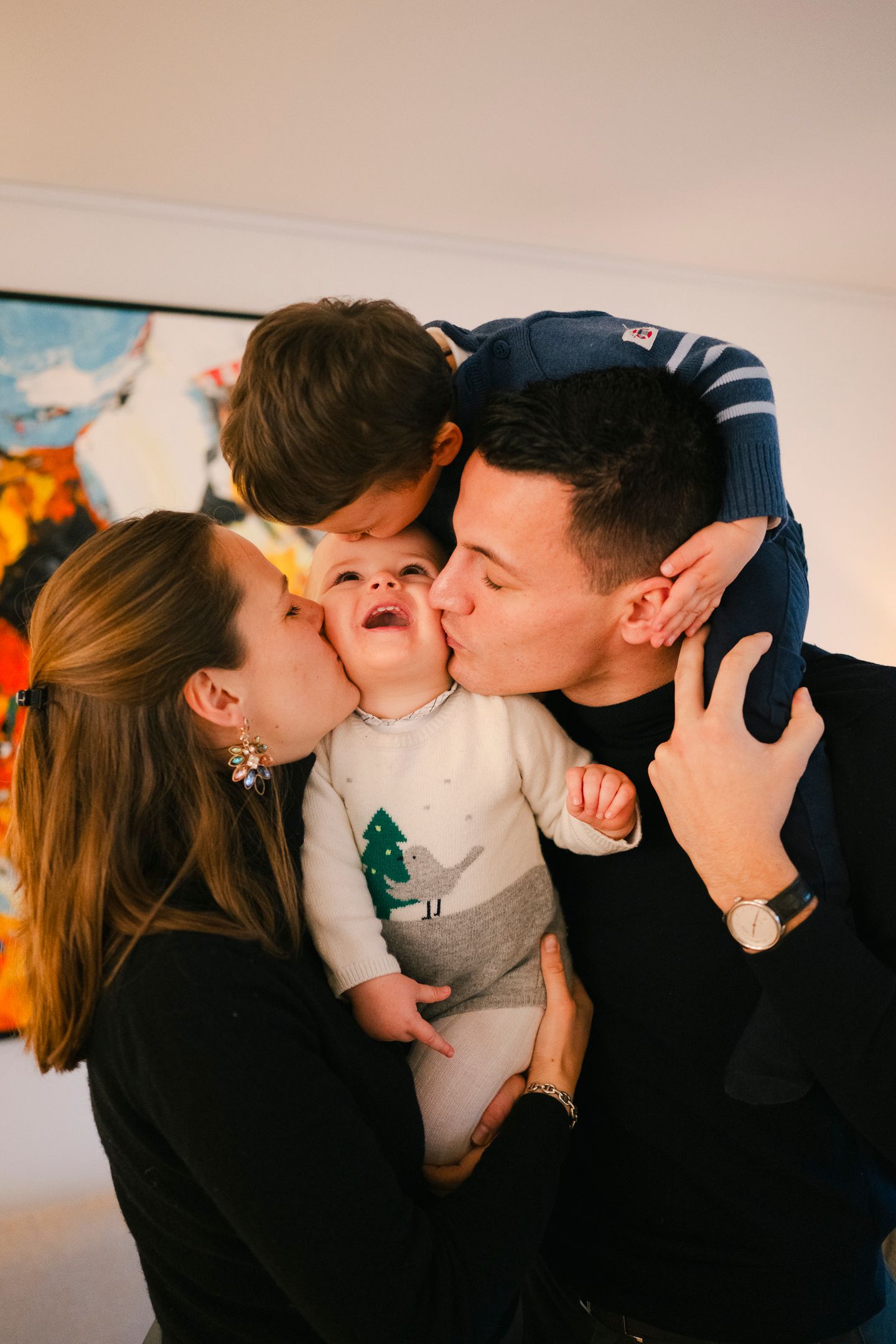 A tender family moment with parents kissing their baby's cheeks.