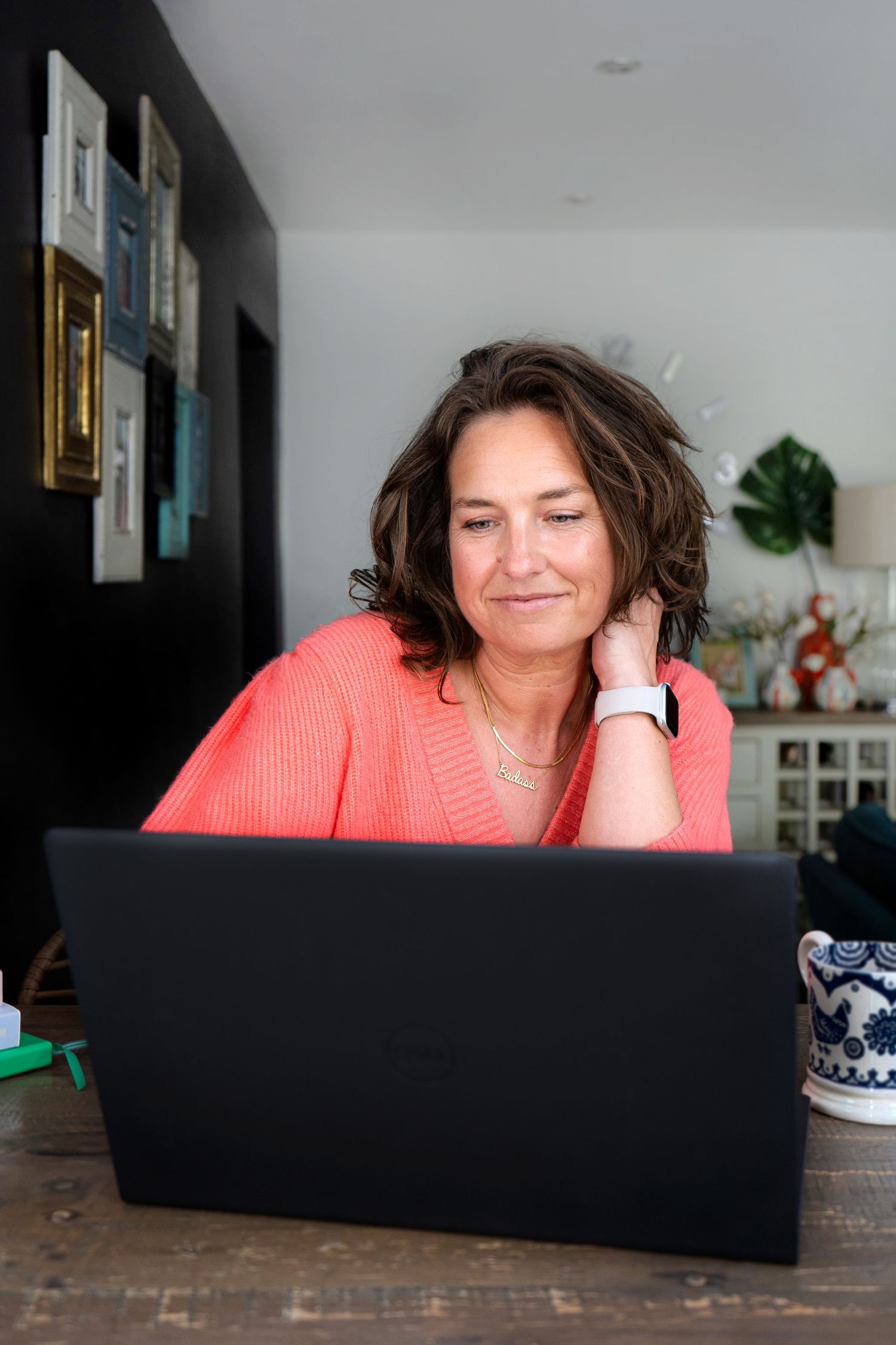 Workspace setup with laptop computer on dark wooden surface in home office setting. Female smiling brand portrait