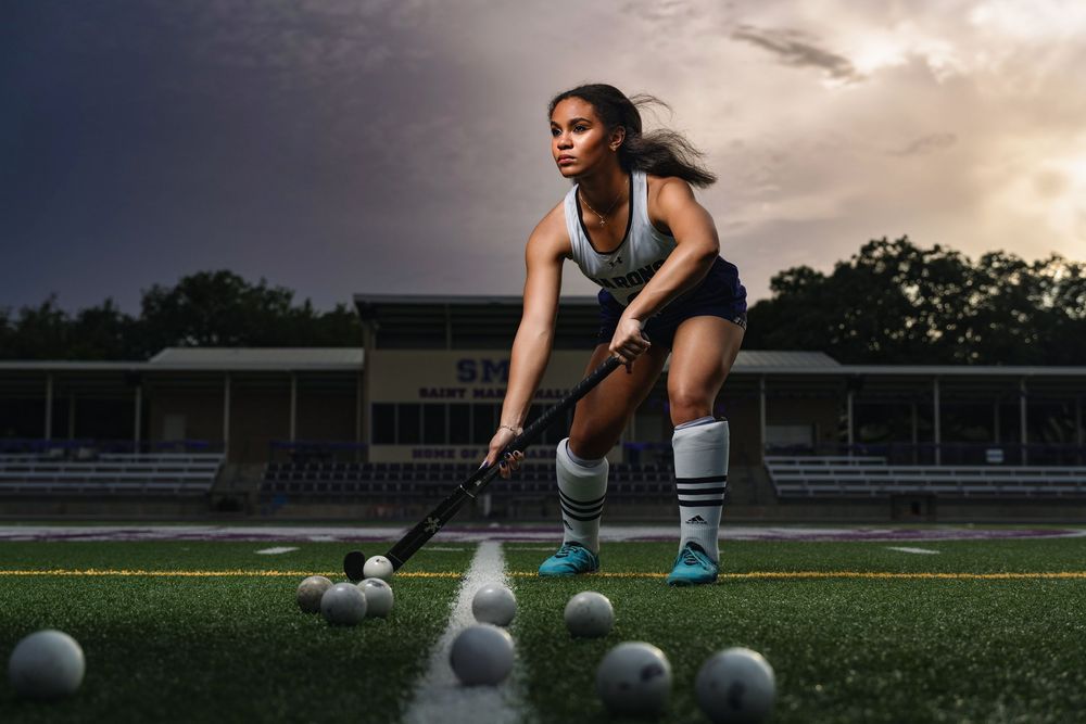Athlete practicing soccer drills on field at dusk with multiple soccer balls scattered on the grass.
