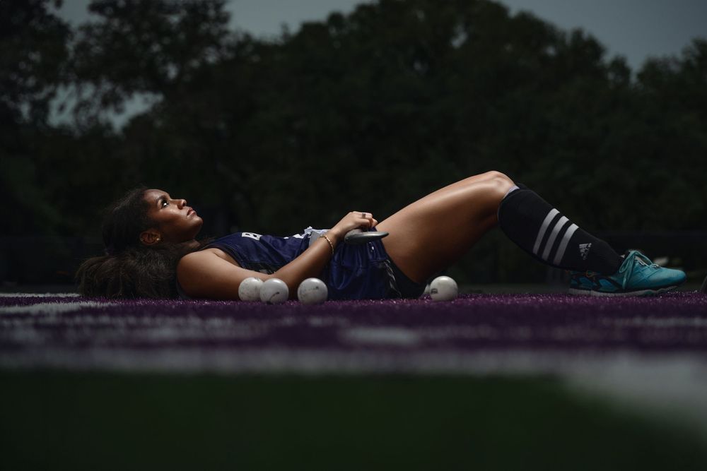 Tennis player lies on court with tennis balls scattered around during moody evening practice session.