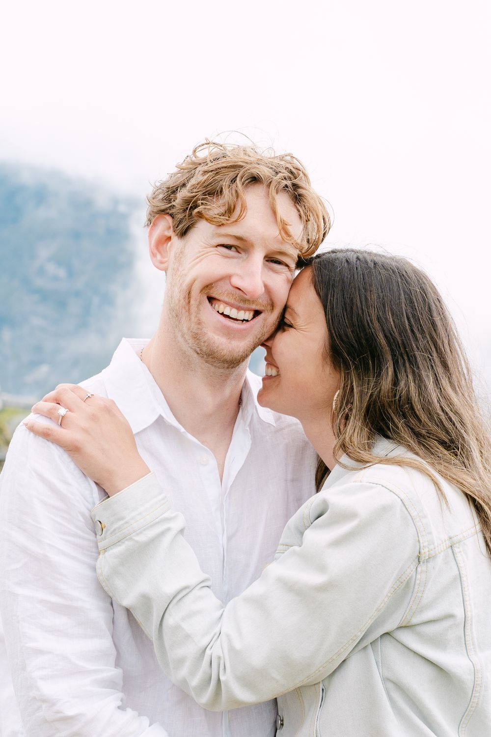 A romantic couple in white clothing share intimate moments together against a soft blurred background.