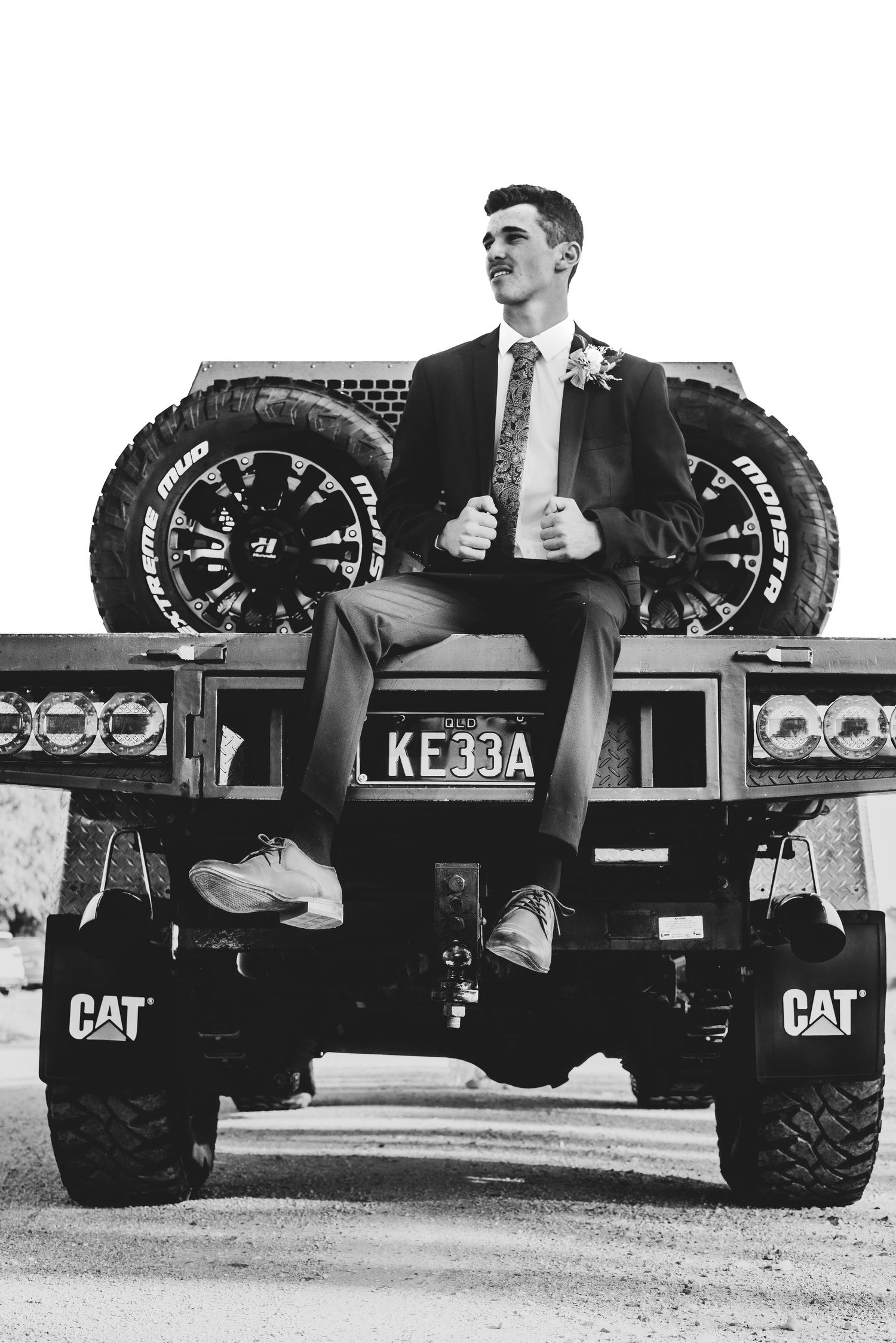 A person in formal attire sits confidently atop a large CAT construction vehicle.