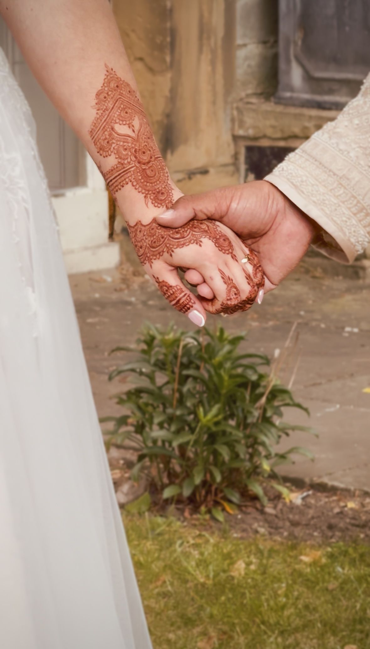 Close up image of the bride and grooms held hands. Detail of the brides wedding henna is shown.