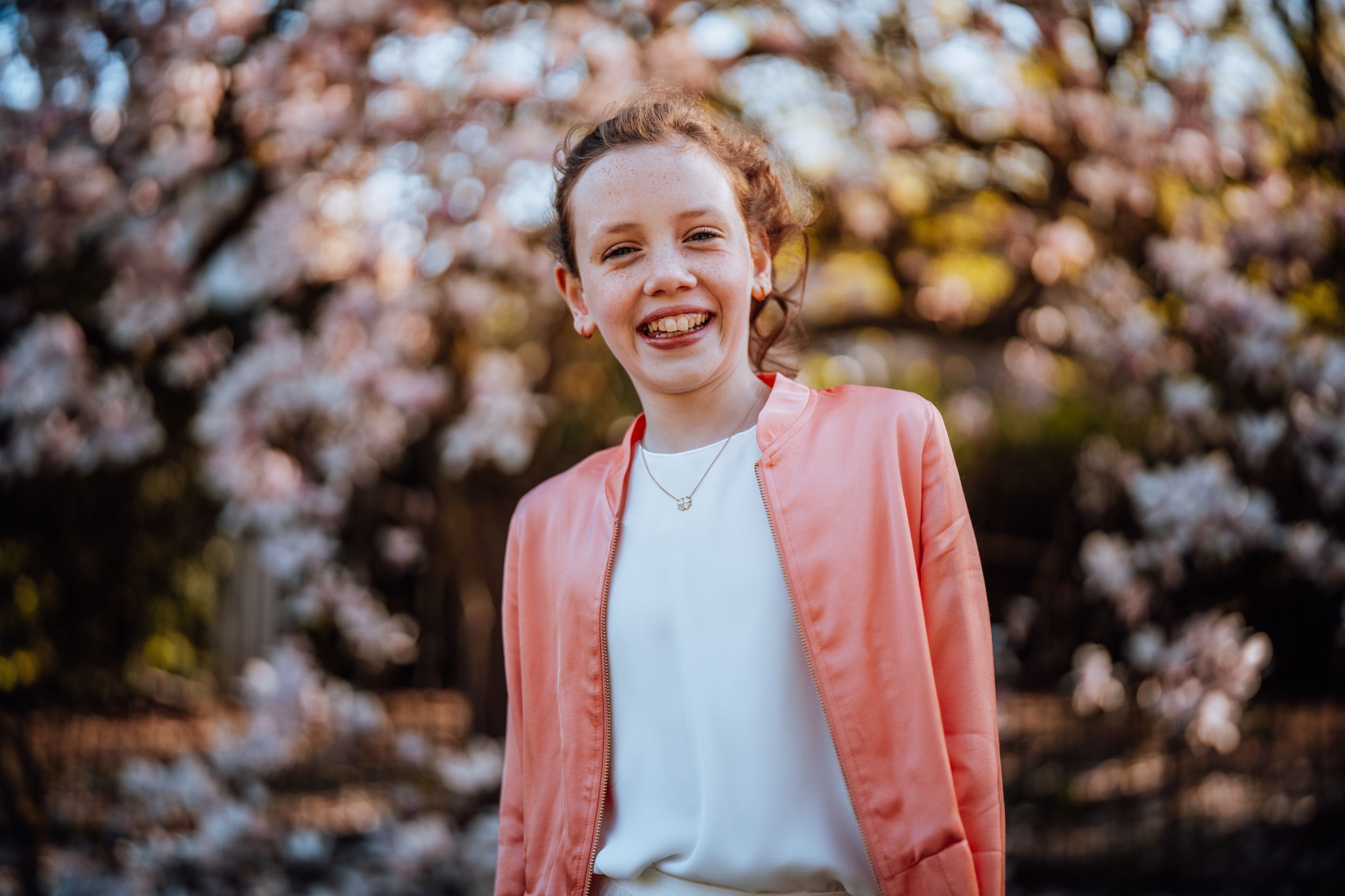 Gelukkige jongere in koraal vest genietend van lentedag met kersenbloesems bloeiend op achtergrond.