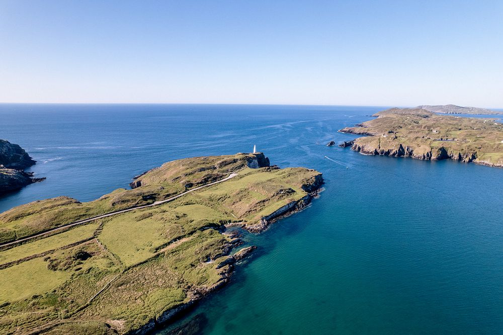 Panoramic aerial view of rugged coastal cliffs and turquoise waters along a dramatic rocky shoreline.