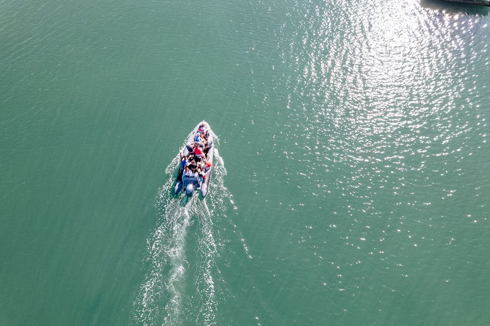 Jet ski rider creates a white wake trail while speeding across turquoise waters on a sunny day.