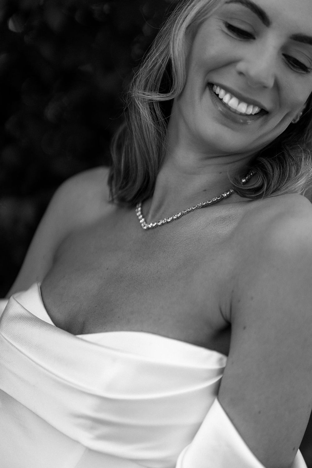 A candid black and white close-up portrait showcasing genuine joy and elegant jewelry.