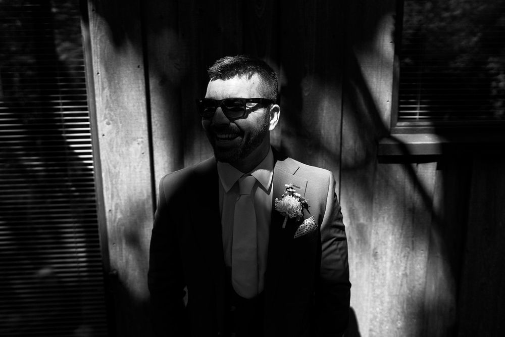 A dramatic black and white portrait of someone in sunglasses and suit with shadows creating contrast.
