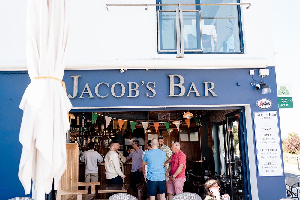 A lively bar scene with patrons gathering at Jacob's Bar while colorful bunting decorates the entrance.