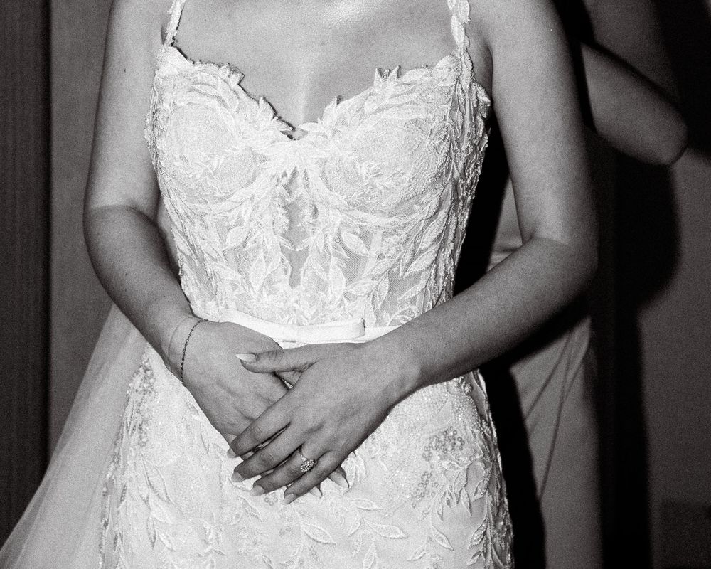 Close-up view of a white lace wedding dress bodice with delicate floral patterns and spaghetti straps.
