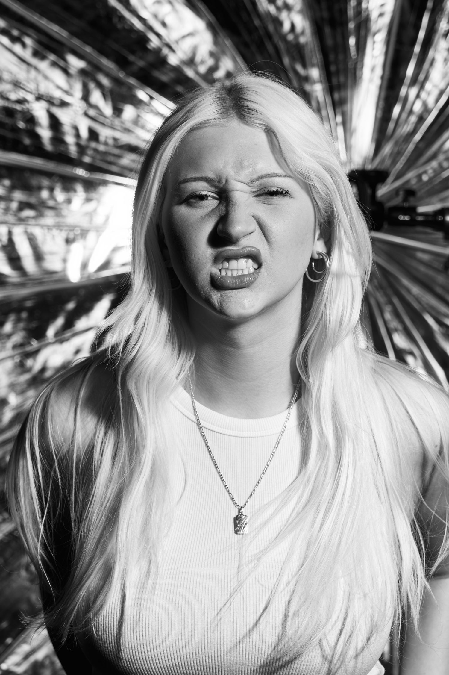 Black and white portrait showing intense emotional expression against palm frond background.