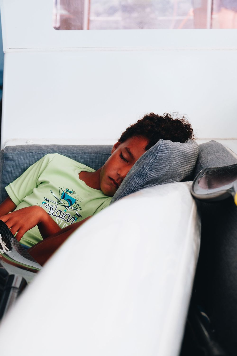 Someone naps peacefully on a couch wearing a light green t-shirt in a casual home setting.