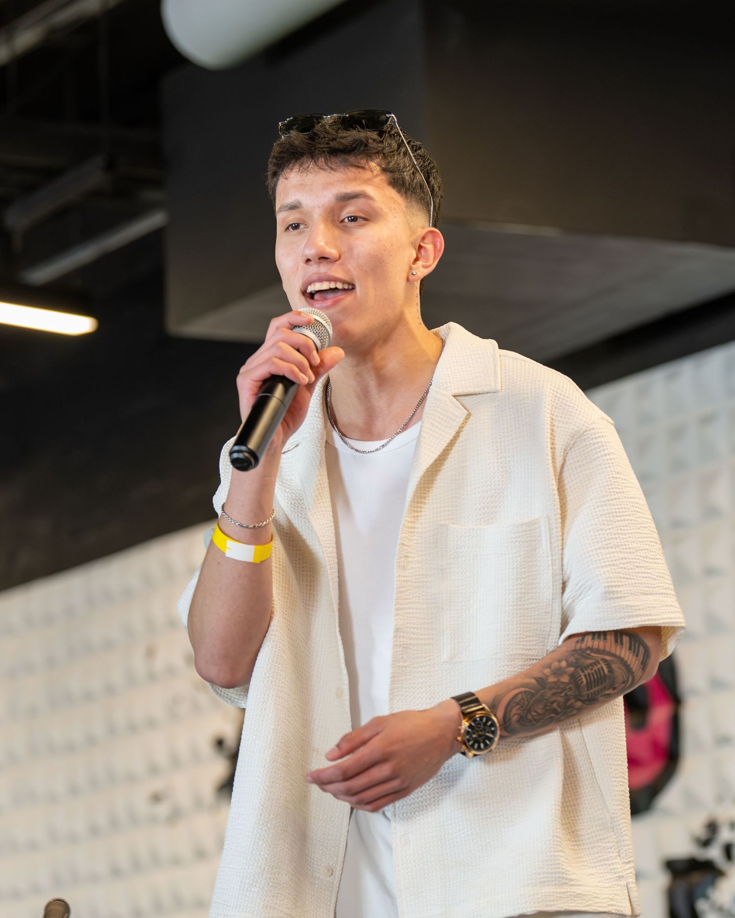 Man singing on a stage at a concert event. He is looking at the audiuence confidently and is authentically himself.