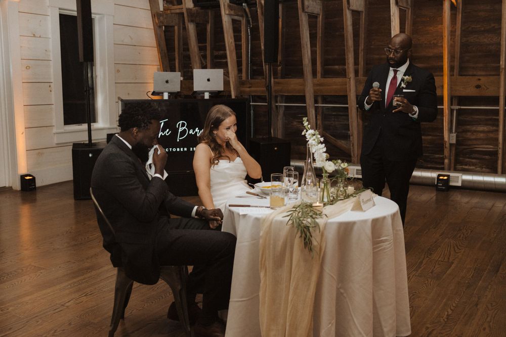 Elegant reception scene with a couple signing documents at a decorated table in a rustic venue.