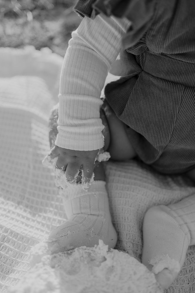 Kleine Hände in weißen Socken greifen nach einer weißen strukturierten Oberfläche.