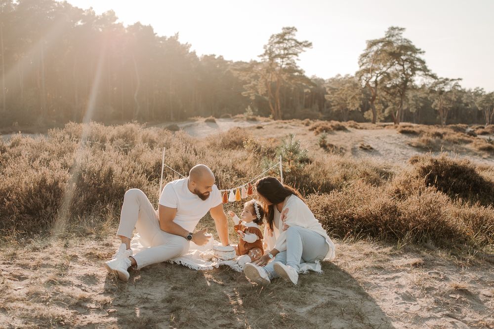 Eine Outdoor-Szene zur goldenen Stunde mit dekorativen Elementen und weißem Stoff, die für eine Fotosession aufgebaut wurden.
