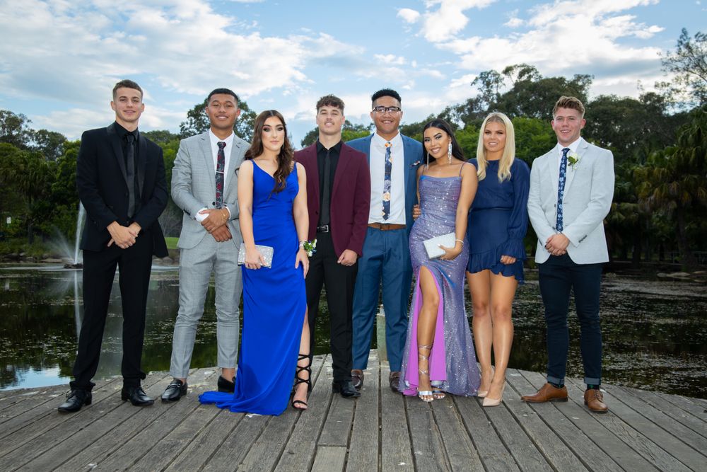 Sydney Event Photography - Formal group photo of people in evening attire standing on a wooden deck with water views.