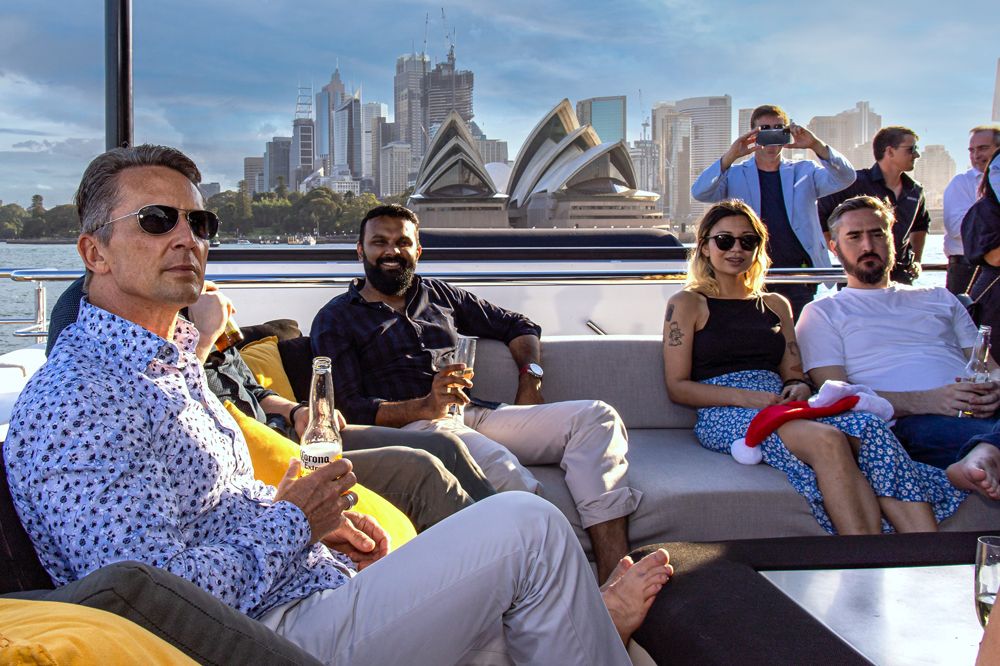 Sydney Event Photography - People enjoying a boat cruise with the Sydney Opera House and city skyline visible in the background.