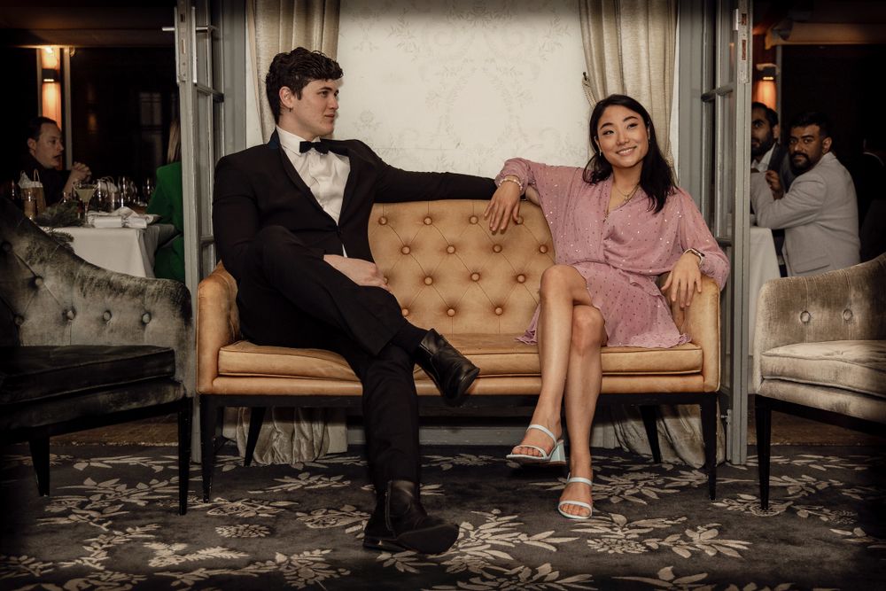 Sydney Event Photography - A couple in formal attire sits on a vintage floral couch at an elegant event.