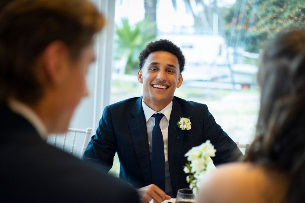 Sydney Event Photography - Person in a navy suit and boutonniere smiling during a formal conversation.