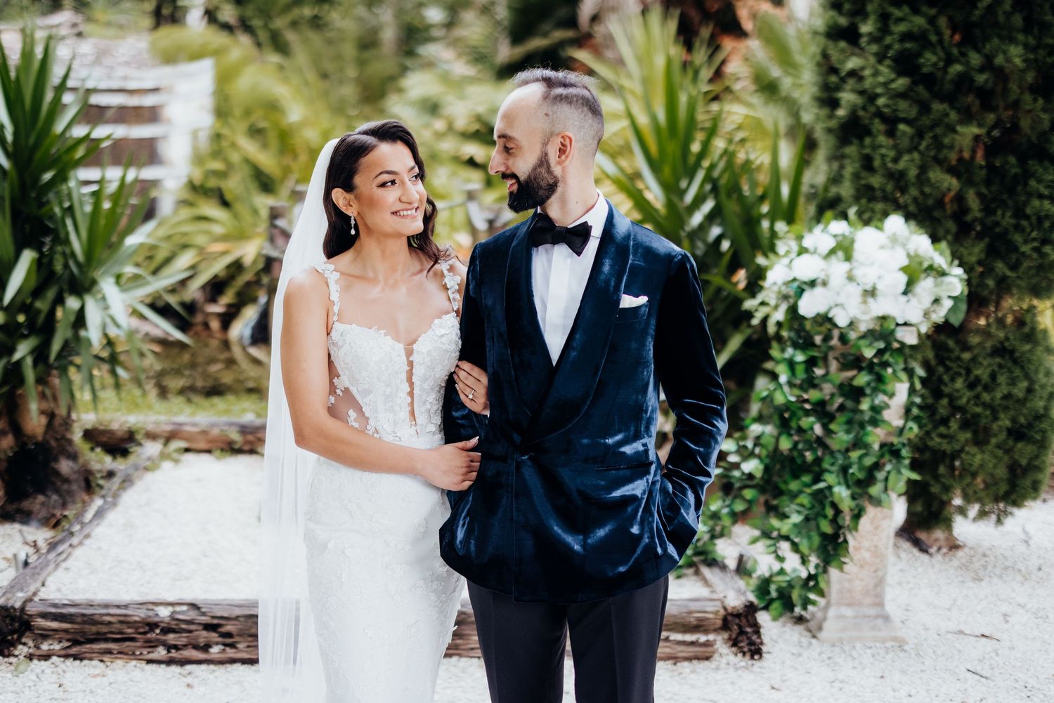 A romantic wedding portrait in a lush garden setting with elegant attire.