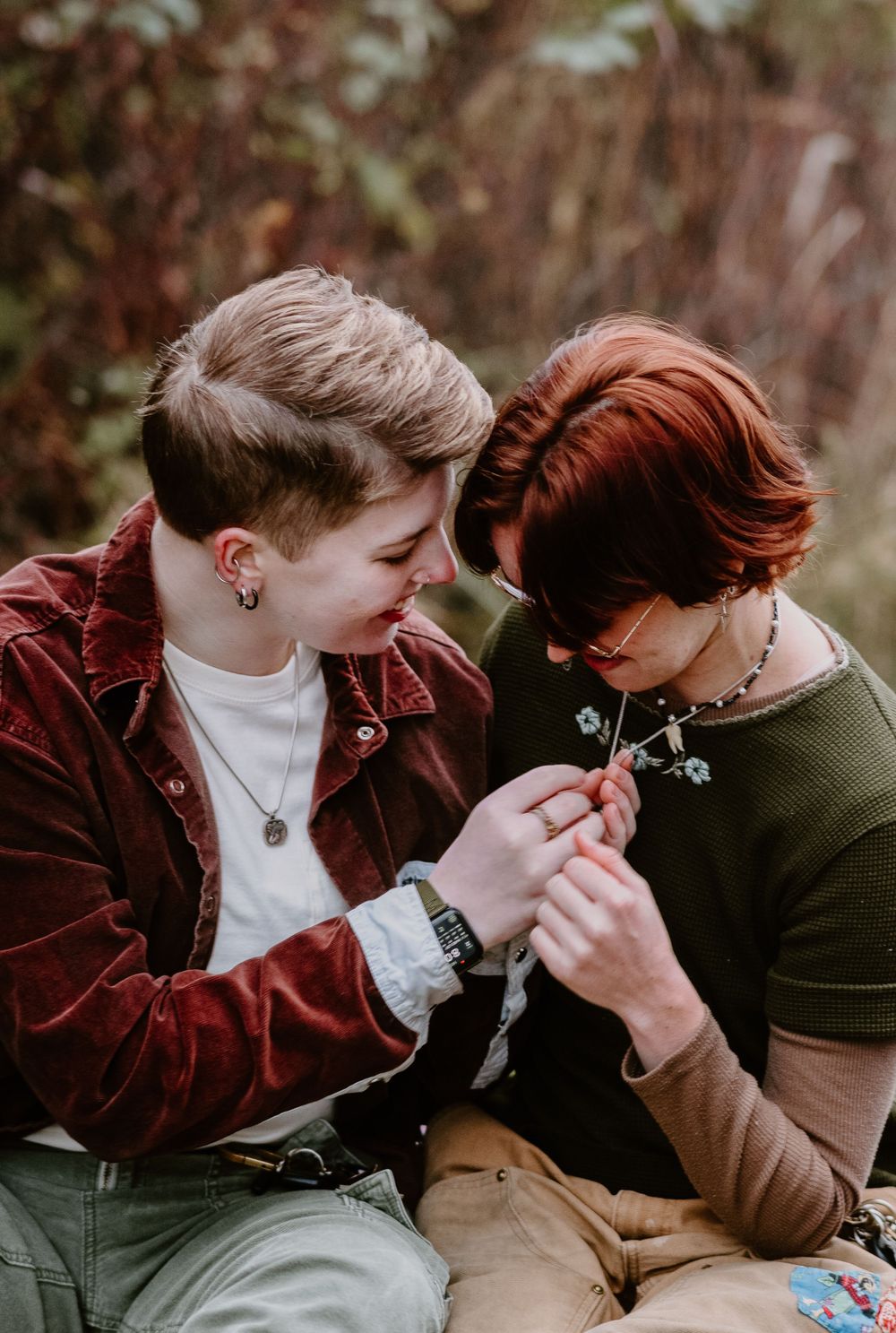 Two people sharing a tender moment while holding hands outdoors in autumn.