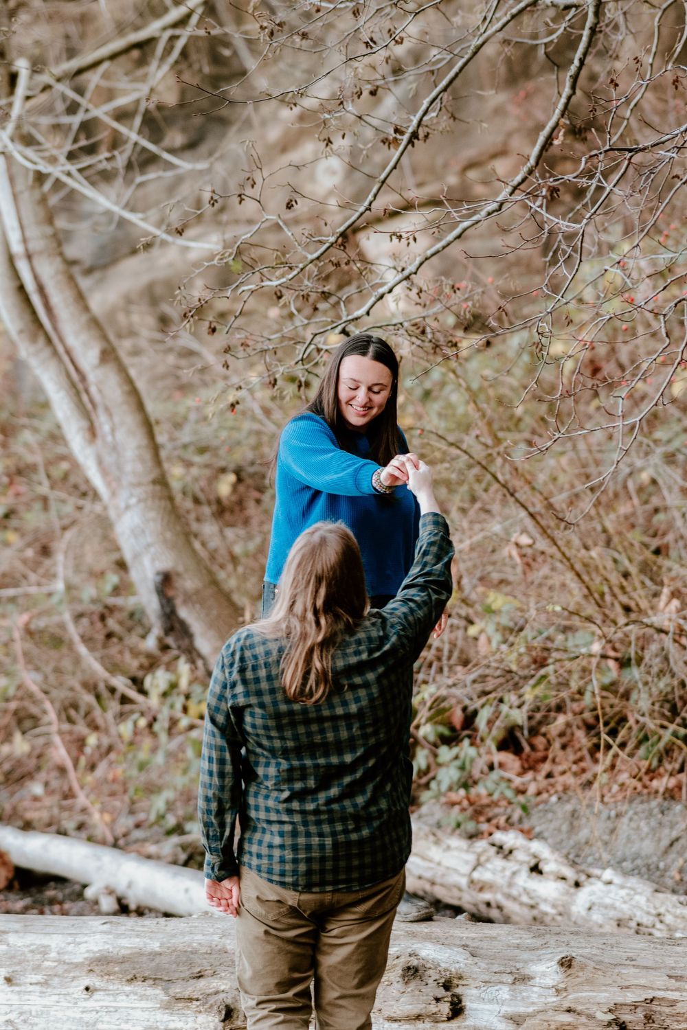 Two people in casual wear dancing together in a natural outdoor setting.