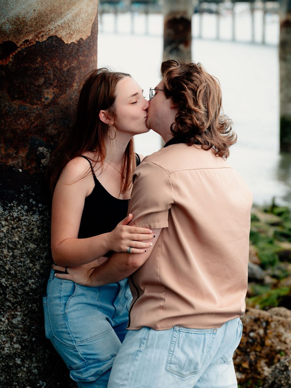 A couple in casual clothing embracing and sharing intimate moments in a naturalistic setting.