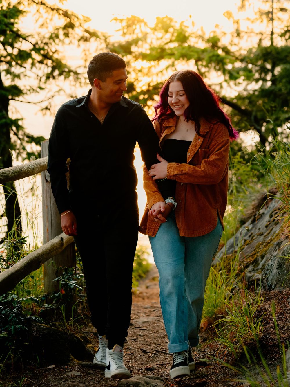 Two people sit together along a scenic woodland trail at sunset.