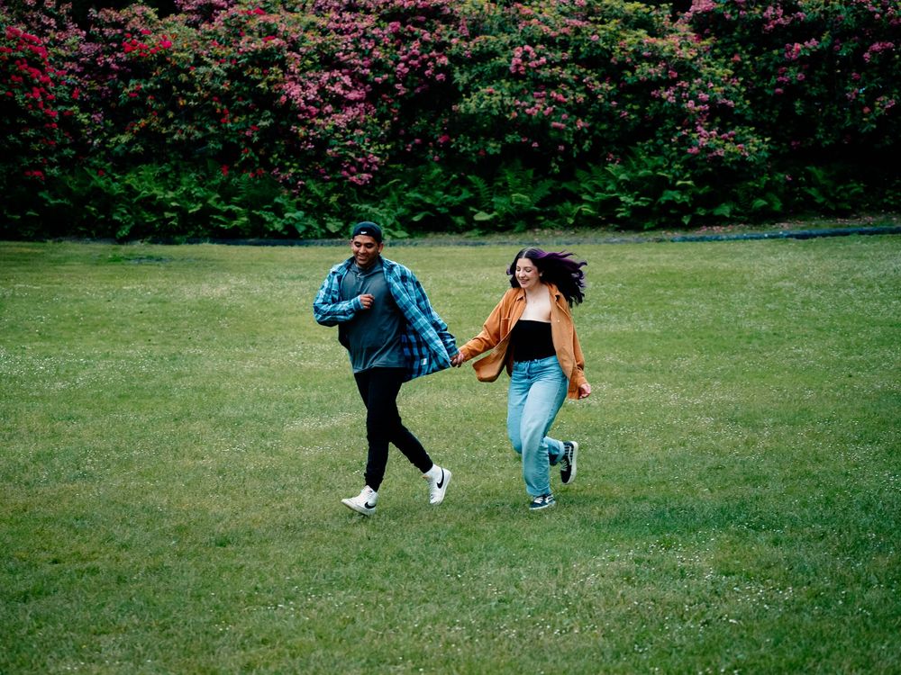 Two people run and play together on a grassy field.