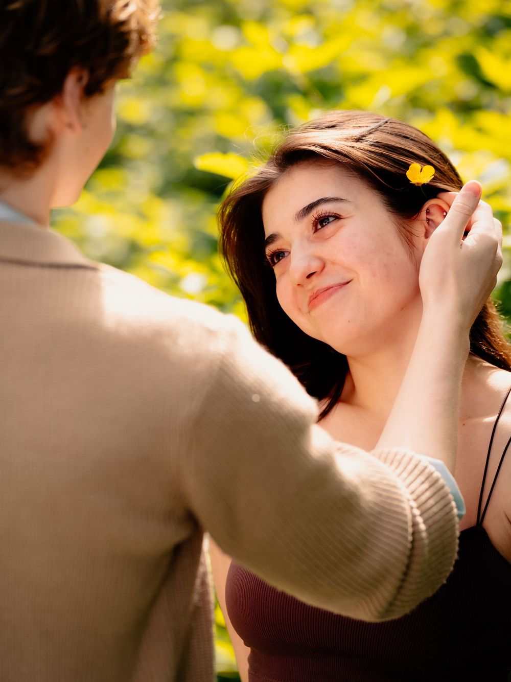 Tender interaction captured against backdrop of bright yellow flowers in sunlight.