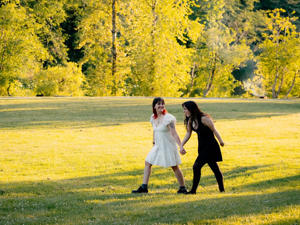 Two people walking and dancing together in a sun-drenched meadow with yellow autumn trees.
